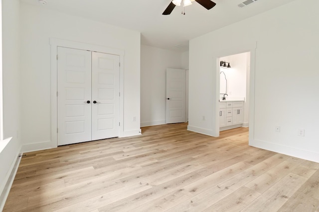 unfurnished bedroom with connected bathroom, visible vents, baseboards, light wood-style floors, and a closet