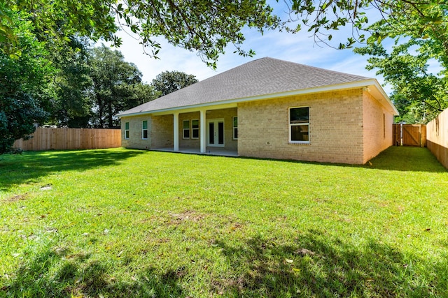 rear view of property with a fenced backyard, brick siding, french doors, a lawn, and a patio area