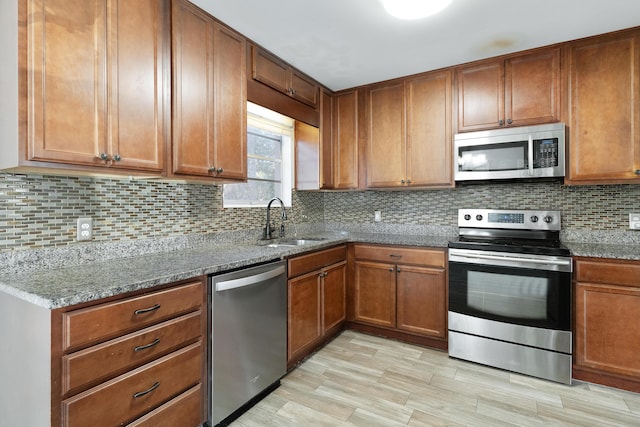 kitchen featuring dark stone countertops, sink, stainless steel appliances, and tasteful backsplash