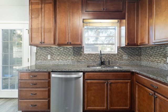 kitchen with dishwasher, sink, dark stone counters, and tasteful backsplash