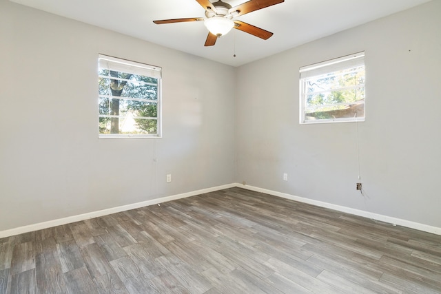 empty room with ceiling fan, a healthy amount of sunlight, and wood-type flooring