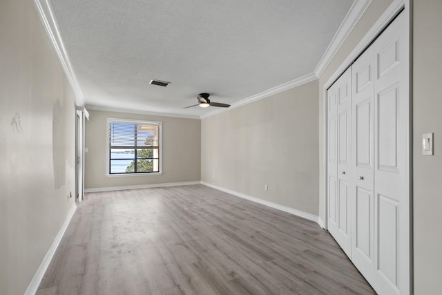 unfurnished bedroom with a textured ceiling, light wood-type flooring, ceiling fan, and crown molding