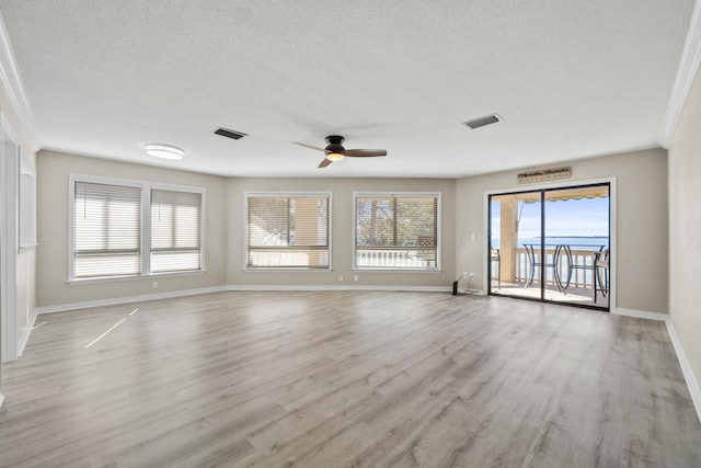 unfurnished living room featuring ceiling fan, ornamental molding, a textured ceiling, and light wood-type flooring