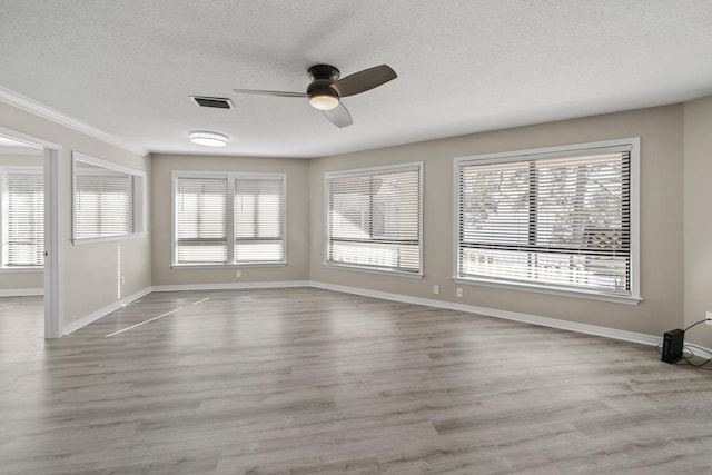 unfurnished room with ceiling fan, light hardwood / wood-style floors, a textured ceiling, and a wealth of natural light