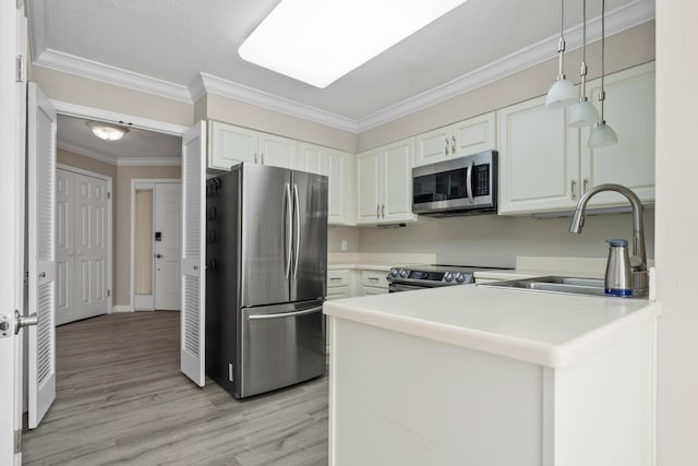 kitchen with kitchen peninsula, stainless steel appliances, sink, decorative light fixtures, and white cabinetry