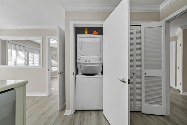 laundry room featuring a textured ceiling, light wood-type flooring, stacked washer / dryer, and ornamental molding