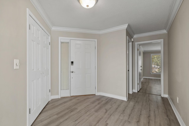 entrance foyer with a textured ceiling, light hardwood / wood-style floors, and ornamental molding