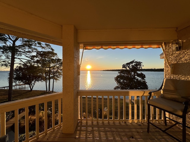 deck at dusk featuring a water view