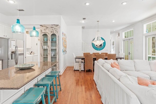 living room with a chandelier, washing machine and dryer, and light hardwood / wood-style floors