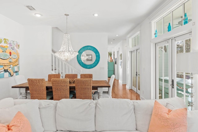 dining space with a chandelier, light hardwood / wood-style floors, and french doors