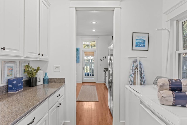 interior space with separate washer and dryer, white cabinetry, a healthy amount of sunlight, and light hardwood / wood-style flooring