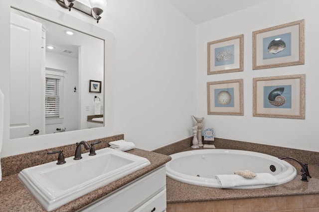 bathroom with tiled bath and vanity