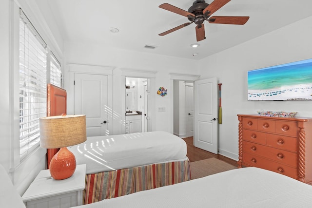 bedroom with ceiling fan, dark wood-type flooring, and connected bathroom