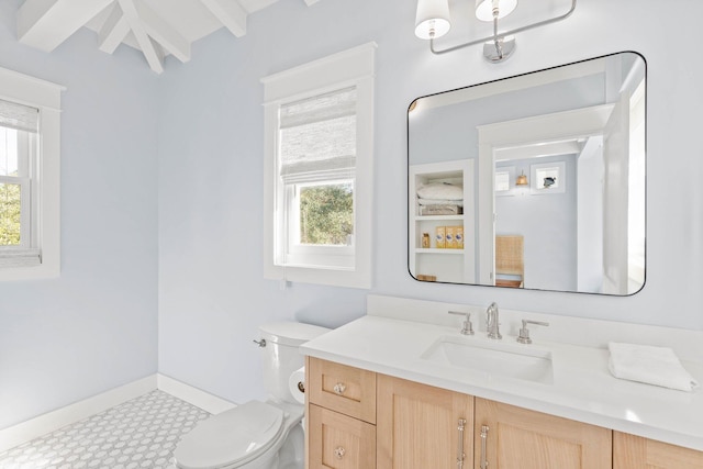 bathroom with beam ceiling, vanity, toilet, and a wealth of natural light