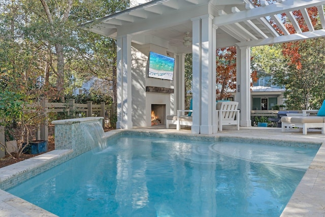 view of pool featuring pool water feature, ceiling fan, and exterior fireplace