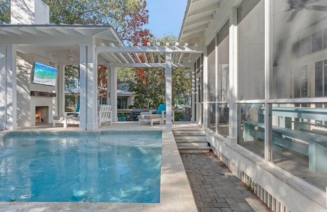 view of swimming pool featuring exterior fireplace, a patio area, and ceiling fan