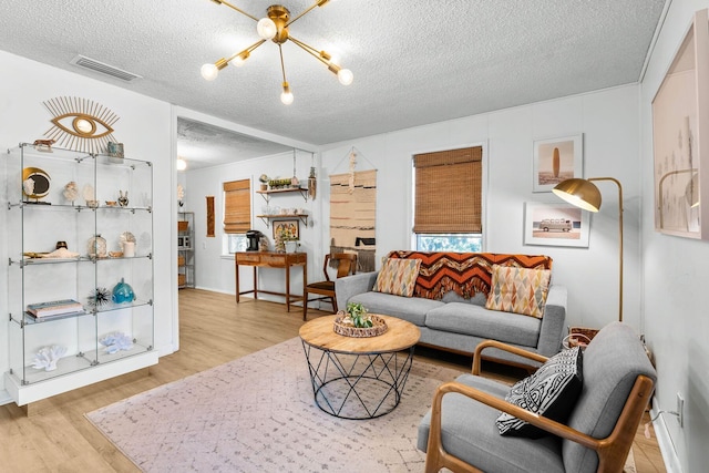 living room with light hardwood / wood-style flooring, a chandelier, and a textured ceiling