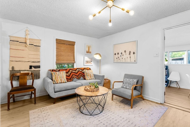 living room featuring wood-type flooring, a textured ceiling, and an inviting chandelier