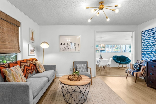 living room featuring light hardwood / wood-style flooring, a textured ceiling, and a notable chandelier