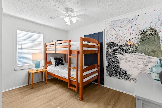 bedroom with ceiling fan, light hardwood / wood-style floors, a textured ceiling, and ornamental molding