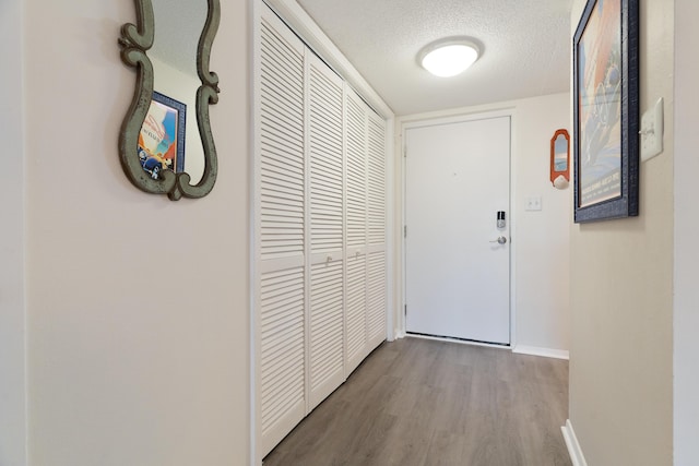 corridor with a textured ceiling and light hardwood / wood-style flooring