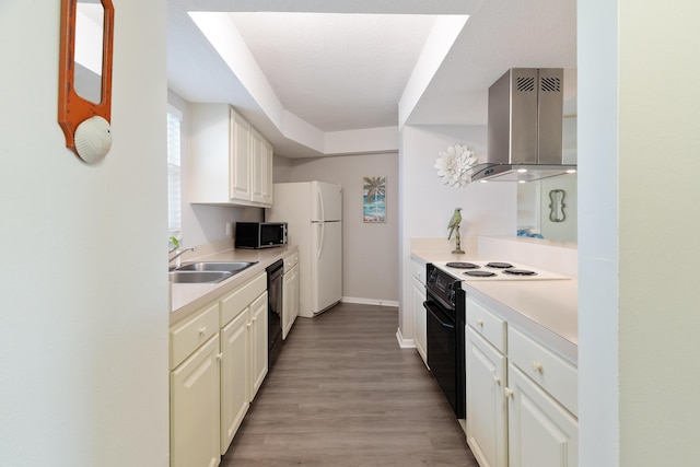 kitchen with black appliances, white cabinets, sink, light hardwood / wood-style flooring, and wall chimney exhaust hood