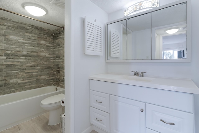 full bathroom featuring vanity, a textured ceiling, hardwood / wood-style floors, toilet, and tiled shower / bath