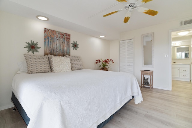 bedroom with ensuite bath, ceiling fan, a closet, and light hardwood / wood-style flooring