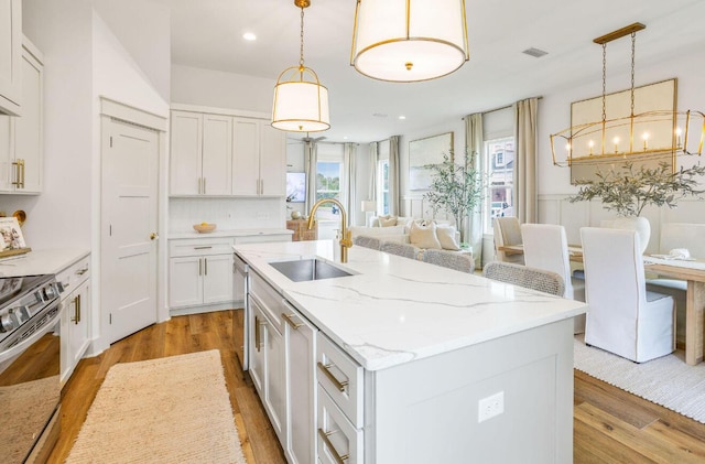 kitchen featuring stainless steel appliances, a center island with sink, hanging light fixtures, and sink