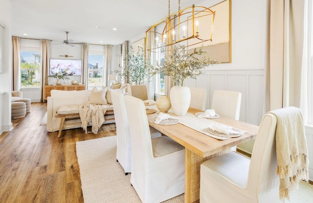 dining area featuring wood-type flooring and ceiling fan with notable chandelier