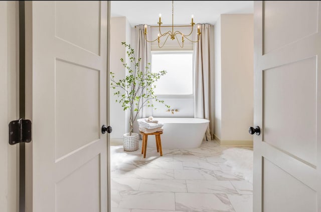 bathroom with a tub to relax in and a notable chandelier