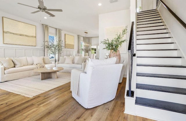 living room featuring wood-type flooring and ceiling fan with notable chandelier