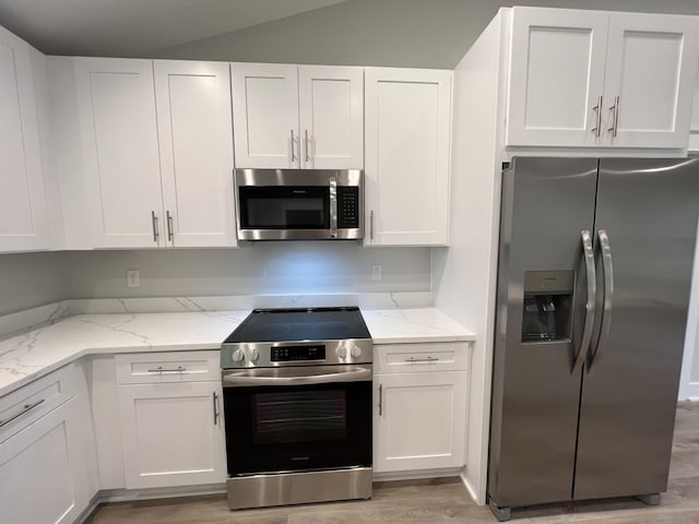 kitchen with light stone counters, white cabinets, and appliances with stainless steel finishes