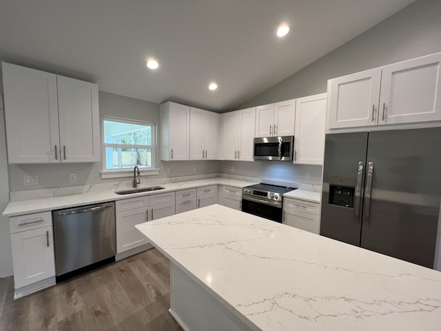 kitchen featuring sink, white cabinetry, vaulted ceiling, and appliances with stainless steel finishes