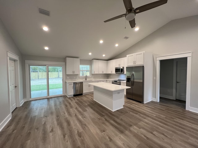 kitchen with vaulted ceiling, stainless steel appliances, ceiling fan, a kitchen island, and white cabinetry