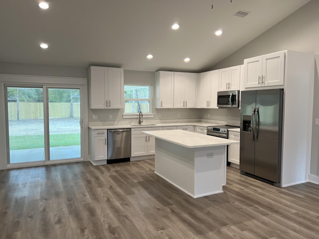 kitchen with wood-type flooring, stainless steel appliances, a center island, white cabinetry, and lofted ceiling