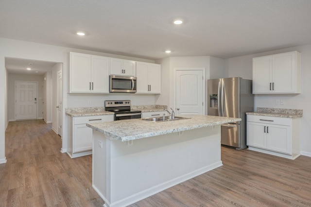 kitchen with appliances with stainless steel finishes, an island with sink, white cabinetry, and sink