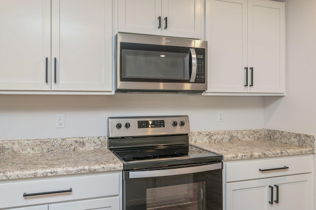 kitchen with light stone counters, white cabinetry, and appliances with stainless steel finishes