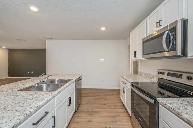 kitchen with sink, light hardwood / wood-style flooring, a textured ceiling, appliances with stainless steel finishes, and white cabinetry