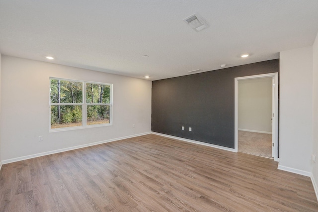 unfurnished room with a textured ceiling and light hardwood / wood-style flooring