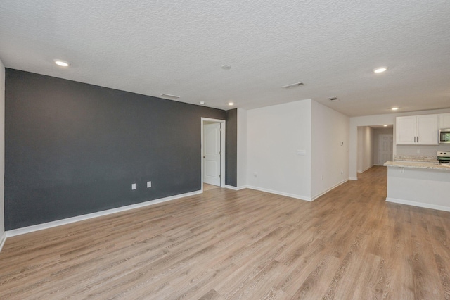 unfurnished living room with a textured ceiling and light hardwood / wood-style floors