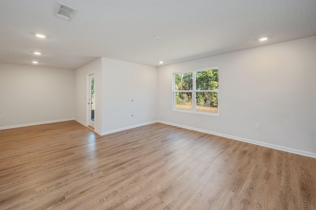 unfurnished room featuring a textured ceiling and light wood-type flooring