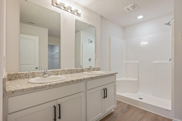 bathroom featuring a shower, vanity, a textured ceiling, and hardwood / wood-style flooring