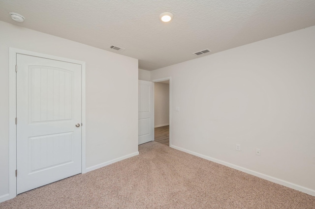 unfurnished bedroom featuring light colored carpet and a textured ceiling