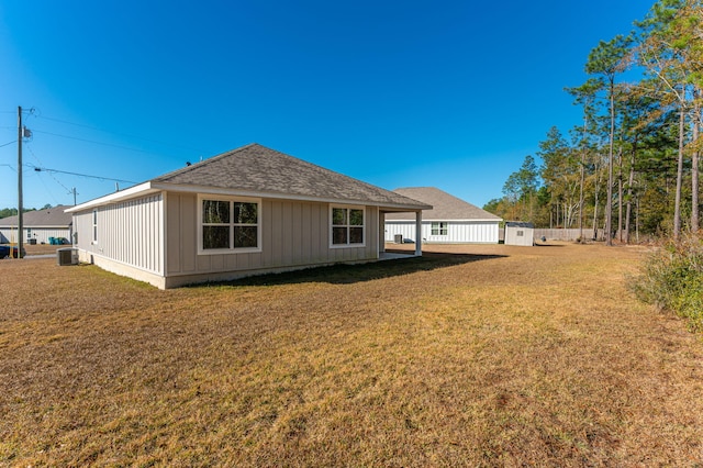 rear view of property featuring a lawn and cooling unit