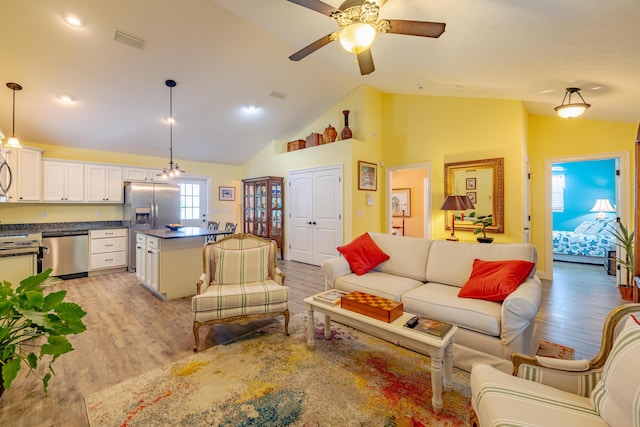 living room with light wood-type flooring, high vaulted ceiling, and ceiling fan