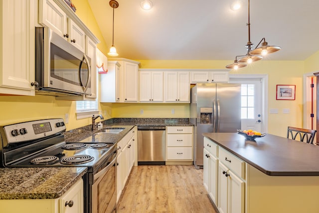 kitchen with white cabinets, sink, appliances with stainless steel finishes, decorative light fixtures, and a kitchen island