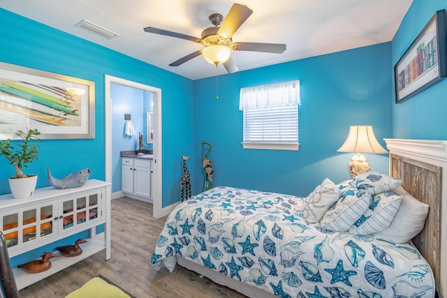 bedroom with ceiling fan, light hardwood / wood-style flooring, and ensuite bath