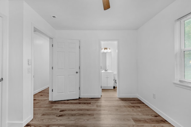 unfurnished bedroom featuring light wood-type flooring, connected bathroom, ceiling fan, and sink