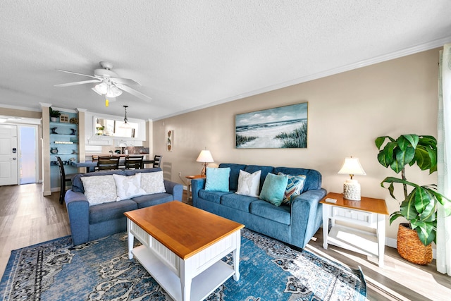 living room with ceiling fan, ornamental molding, and a textured ceiling